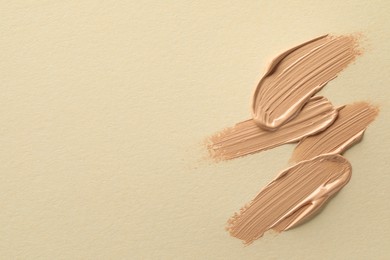 Sample of liquid skin foundation on beige background, top view. Space for text