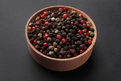 Wooden bowl of peppercorn mix on dark background