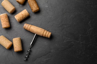 Corkscrew and wine bottle stoppers on slate table, flat lay. Space for text
