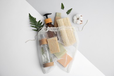 Mesh bag with eco friendly personal care products on color background, flat lay
