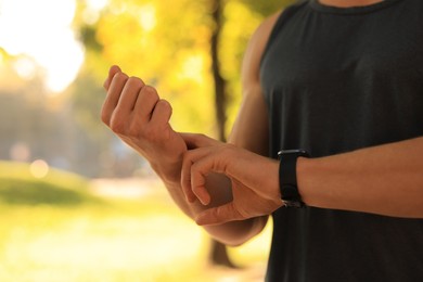 Man checking pulse after training on sunny day, closeup