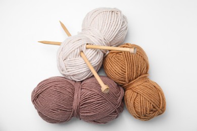 Photo of Soft woolen yarns and knitting needles on white background, top view