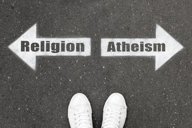 Image of Choice between atheism and religion. Woman standing on road near arrows marking, top view