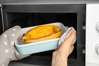 Woman taking baked spaghetti squash out of microwave oven, closeup