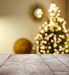 Empty wooden surface and blurred view of Christmas tree in room, space for text. Interior design