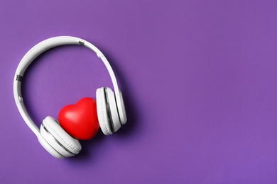 Modern headphones and red heart on purple background, flat lay with space for text. Listening love music songs