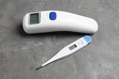 Non-contact infrared and digital thermometers on grey stone background