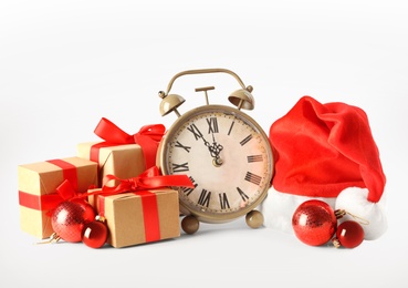 Photo of Alarm clock with gifts and festive decor on white background. New Year countdown