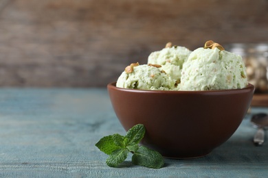 Delicious pistachio ice cream in bowl on blue wooden table. Space for text