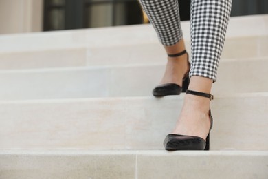 Photo of Woman in stylish black shoes walking down stairs, closeup
