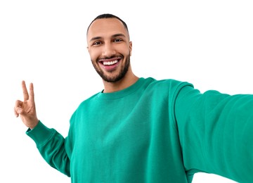 Photo of Smiling young man taking selfie and showing peace sign on white background