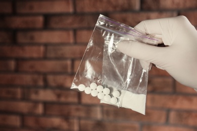 Police worker holding drugs in plastic bags, closeup. Space for text