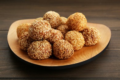 Photo of Many delicious sesame balls on wooden table, closeup