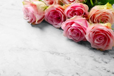 Photo of Beautiful bouquet of roses on white marble table, space for text. Happy birthday greetings