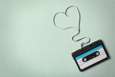 Top view of music cassette and heart made with tape on turquoise background, space for text. Listening love song