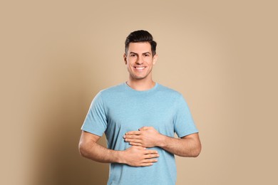 Happy healthy man touching his belly on beige background