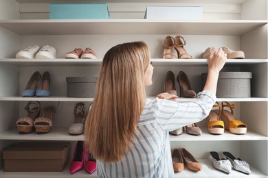 Woman near rack with shoes indoors, back view. Interior design