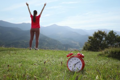 Woman doing morning exercise in mountains, focus on alarm clock