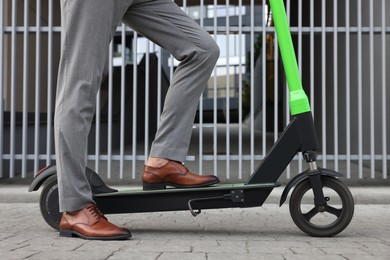 Businessman with modern kick scooter on city street, closeup