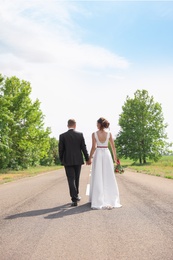 Bride and groom walking away on highway