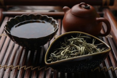Photo of Aromatic Baihao Yinzhen tea and teapot on wooden tray, closeup. Traditional ceremony