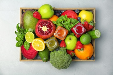 Crate with healthy detox smoothies and ingredients on light background, top view