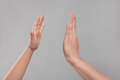 Photo of Mother and daughter giving high five on light grey background, closeup of hands