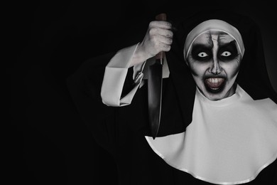 Scary devilish nun with knife on black background, space for text. Halloween party look