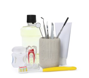 Tooth model, oral hygiene products and dentist tools on white background