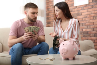 Photo of Unhappy young couple with money at home. Financial problems