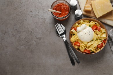 Bowl of delicious pasta with burrata and tomatoes served on grey table, flat lay. Space for text