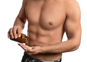 Athletic man with bottle of pills on white background, closeup. Doping concept