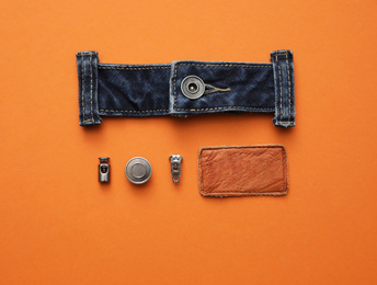 Photo of Flat lay composition with garment accessories and cutting details for jeans on orange background