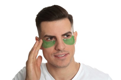 Man applying green under eye patch on white background