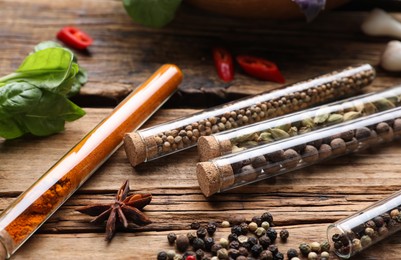 Fragrant spices in glass test tubes on wooden table, closeup