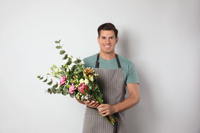 Florist with beautiful bouquet on light background