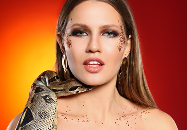 Beautiful woman with boa constrictor on bright colorful background, closeup
