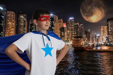 Teenage boy wearing superhero costume and beautiful cityscape in night on background