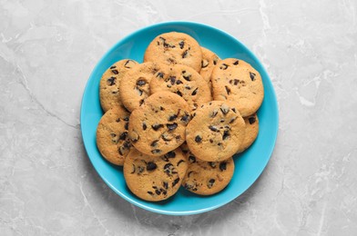 Plate with delicious chocolate chip cookies on grey marble table, top view