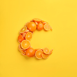 Letter C made with citrus fruits on yellow background as vitamin representation, flat lay