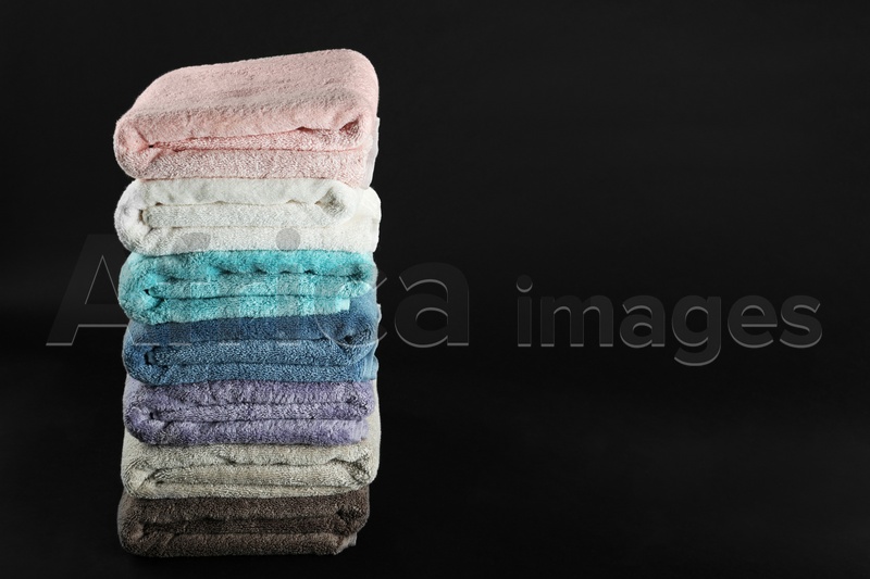 Different fresh soft terry towels on dark background. Space for text