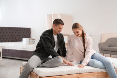 Happy couple choosing mattress in furniture store