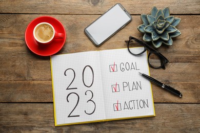 Flat lay composition of notebook with text 2023 Goal, Plan, Action on wooden table. New year resolutions