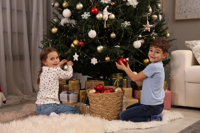 Cute little children decorating Christmas tree at home