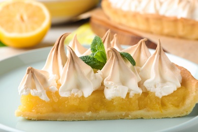 Piece of delicious lemon meringue pie with mint on plate, closeup