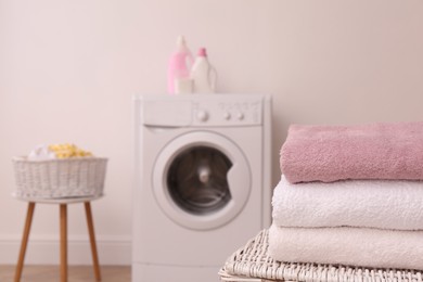 Clean folded towels on wicker basket in laundry room. Space for text