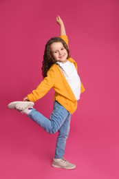 Full length portrait of cute little girl on pink background