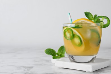 Photo of Spicy cocktail with jalapeno, lemon and mint on white marble table. Space for text