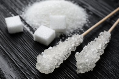 Photo of Different types of sugar on black wooden table, closeup