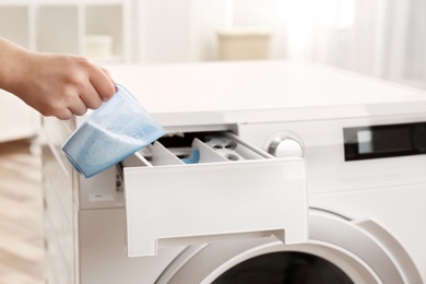 Woman pouring powder into drawer of washing machine indoors, closeup. Laundry day